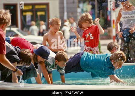 Bambini che giocano alla fontana di Rynek (Piazza del mercato) a Wadowice (luogo di nascita di Papa Giovanni Paolo II), regione di Malopolska, Polonia Foto Stock