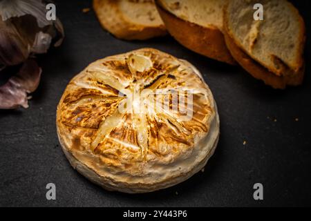 Formaggio Brie o camembert cotto al forno su sfondo nero con pane tostato o pane tostato e aglio. Foto di alta qualità Foto Stock