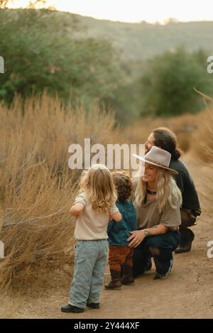 La famiglia sul sentiero naturalistico guarda i fiori Foto Stock