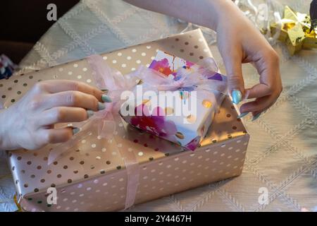 Le mani della donna legano il nastro a due regali splendidamente avvolti Foto Stock