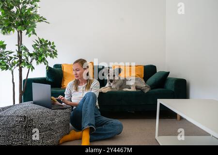 donna freelance che lavora su un portatile con il suo cane a casa Foto Stock