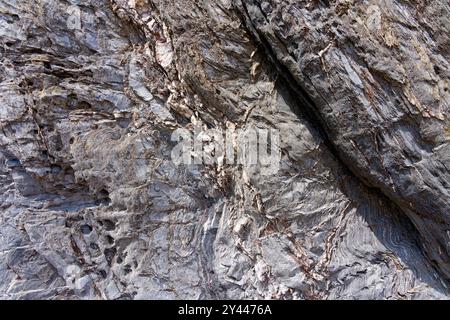 Superficie aspra di un pezzo di roccia lavica grigia-argento trovato sulla spiaggia di Hemmick, Cornovaglia. Foto Stock