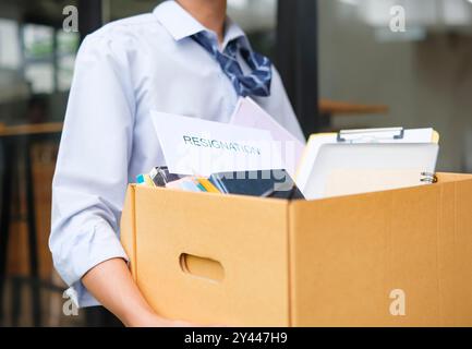 Uomo d'affari che lascia l'ufficio dopo le dimissioni da Box of Bavings Foto Stock