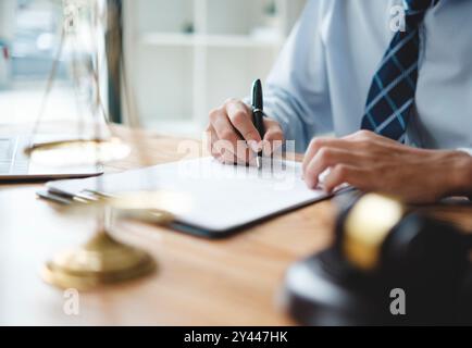Un avvocato in causa è seduto alla sua scrivania, a firmare documenti legali Foto Stock