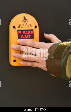 Una mano di un uomo preme un sensore del semaforo per accendere il verde Foto Stock