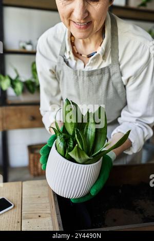 Una donna si prende cura amorevolmente delle sue piante fiorenti nel suo studio illuminato dal sole. Foto Stock