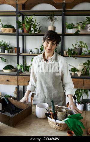 Una donna matura cura amorevolmente le sue piante nel suo studio creativo. Foto Stock