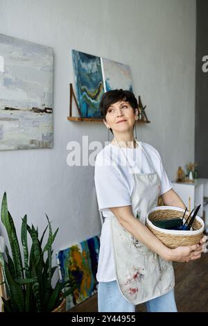 Una pittrice entusiasta si impegna con le sue opere d'arte in un luminoso studio. Foto Stock