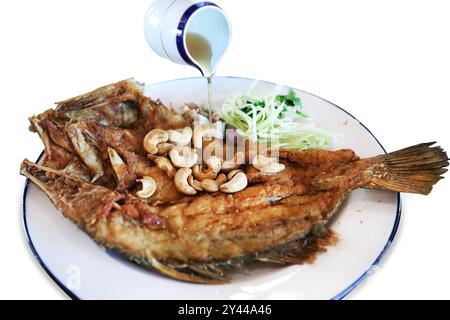 Tagliato di spigola intera fritta con condimento in salsa di pesce e bianco anacardi isolato. Foto Stock