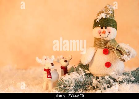 Simpatici pupazzi di neve e cervi con rami di abete sulla neve artificiale Foto Stock