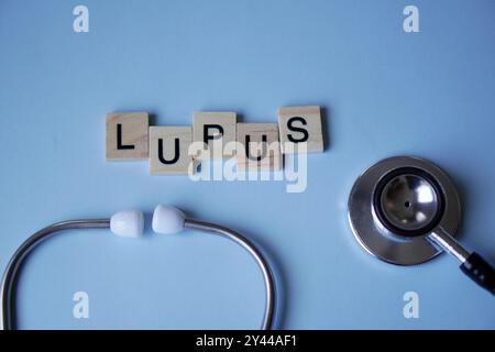 LUPUS, lettere in legno con stetoscopio su sfondo azzurro. concetti di medicina Foto Stock