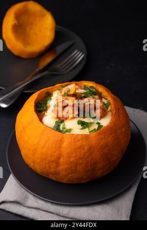 Zucca intera al forno con gamberetti tigre, formaggio fuso e pomodori. Piatto tradizionale del Brasile, cucina casalinga. Messa a fuoco selettiva, primo piano, backgrou nero Foto Stock