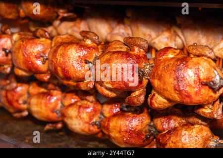 Polli girarrosto che cucinano su spiedini, pasto delizioso, grigliate al barbecue, marroni dorati, pollame arrosto Foto Stock