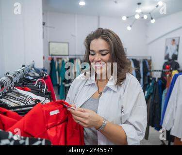 Una donna grassa guarda con orrore al prezzo di un abito in un negozio Plus size. Foto Stock