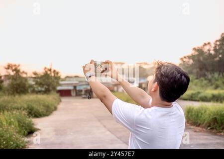 un uomo che sta scattando foto di se stesso e della natura in vari stili. quell'uomo ha le spalle alla telecamera. immersi nella natura in un pomeriggio di sole. Foto Stock