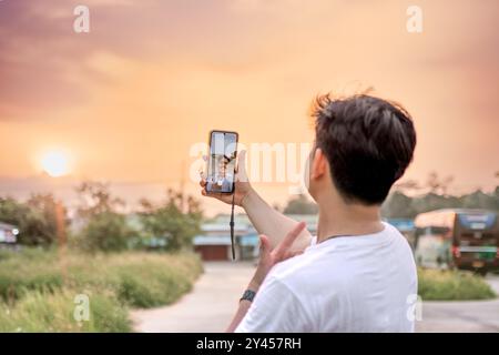 un uomo che sta scattando foto di se stesso e della natura in vari stili. quell'uomo ha le spalle alla telecamera. immersi nella natura in un pomeriggio di sole. Foto Stock