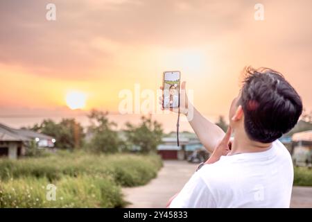 un uomo che sta scattando foto di se stesso e della natura in vari stili. quell'uomo ha le spalle alla telecamera. immersi nella natura in un pomeriggio di sole. Foto Stock