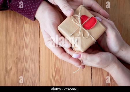 Una donna con un uomo con un regalo in mano su un sfondo di legno il giorno di San Valentino o a Natale. Non vi è spazio libero per il testo. Foto Stock