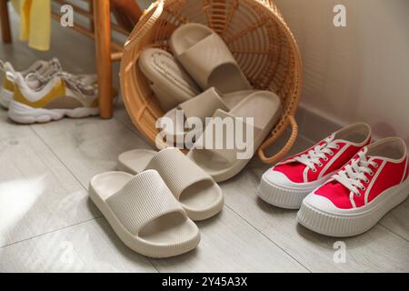 Cestino con pantofole per gli ospiti e scarpe da ginnastica all'ingresso di casa Foto Stock