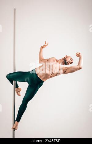 Corpo completo di danzatore muscoloso che tiene con grazia la posa del cucciolo, mostrando forza e flessibilità su sfondo colorato Foto Stock