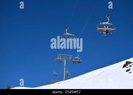 Seggiovie per sciatori e snowboarder in una giornata limpida e soleggiata in una stazione sciistica francese Foto Stock