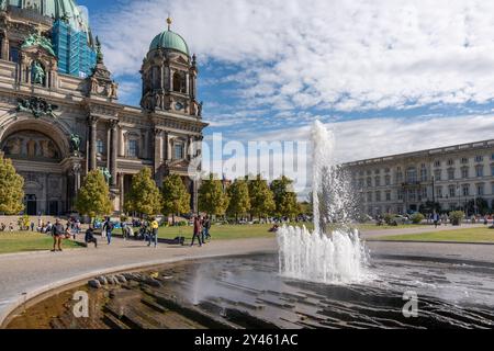 Germania Berlino 15 settembre 2024. Una fontana spruzza acqua nell'aria di fronte a un grande edificio. La fontana è circondata da una folla di pe Foto Stock