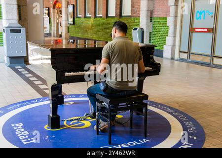 Uomo che suona il pianoforte giovane uomo adulto che suona un pianoforte pubblico all'interno della sala principale della stazione ferroviaria. Maastricht, Paesi Bassi. Maastricht Centraal Station Limburg Nederland Copyright: XGuidoxKoppesxPhotox Foto Stock