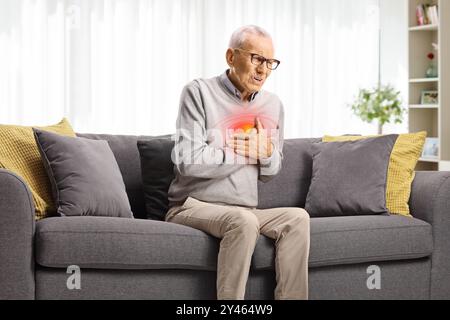 Uomo anziano con arresto cardiaco seduto su un divano in soggiorno Foto Stock