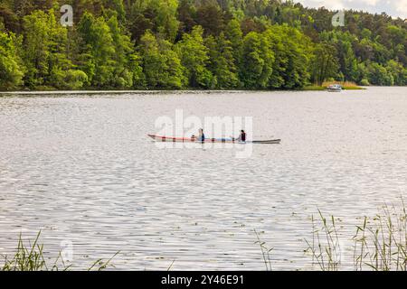 Due persone in kayak sul lago calmo circondato da una lussureggiante foresta verde. Svezia. Uppsala. Foto Stock