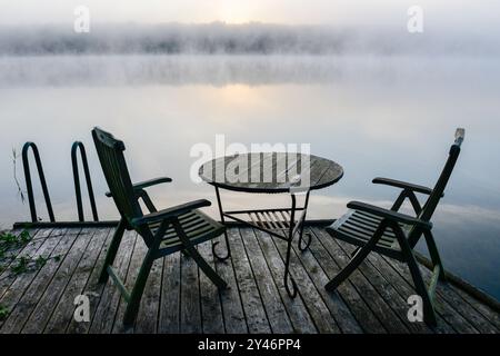 GERMANIA, Plau, sedie e tavolo sul molo sul lago con nebbia / DEUTSCHLAND Plau am SEE, Morgennebel im Spätsommer Foto Stock