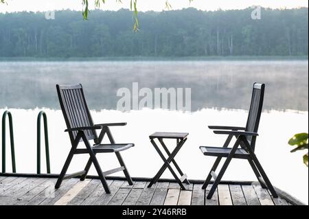 GERMANIA, Plau, sedie e tavolo sul molo sul lago con nebbia / DEUTSCHLAND Plau am SEE, Morgennebel im Spätsommer Foto Stock