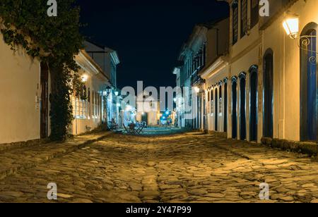 Paraty, Brasile. Quartiere storico di notte. Strada in pietra e case del periodo coloniale. Sullo sfondo, la chiesa Nossa Senhora do Rosário. Foto Stock