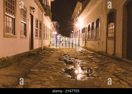 Paraty, Brasile. La strada nel centro storico di notte. Case del periodo coloniale e strade in pietra illuminate da vecchie luci gialle. Foto Stock