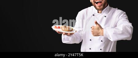 Chef Eccitato Che Mostra Pollo Piatto Gesturante Thumbs-Up, Sfondo Nero, Panorama Foto Stock