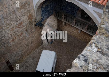 I visitatori camminano attraverso un arco di ciottoli, circondato da mura di pietra Foto Stock