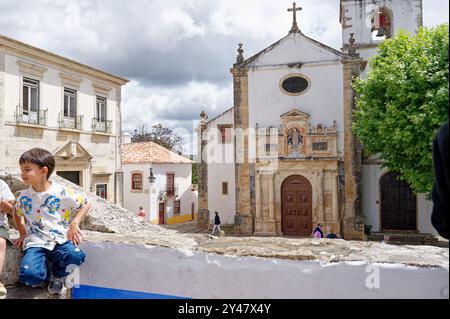 Momenti di gioia davanti alla storica chiesa di Santa Maria, mescolando il patrimonio culturale e giocando sotto un cielo nuvoloso Foto Stock