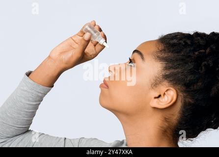 Giovane donna che applica oftalmologia eyedropper, glaucoma prevenzione degli occhi Foto Stock