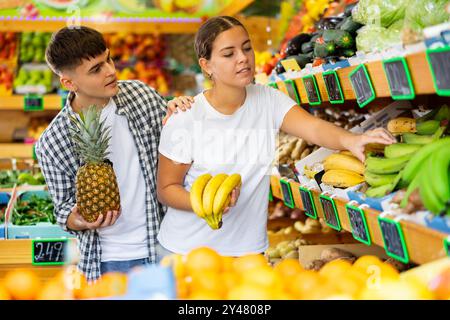 Giovane coppia positiva che sceglie frutta fresca biologica al supermercato Foto Stock