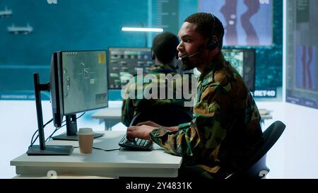 I soldati in una sala di controllo militare all'avanguardia collaborano all'analisi dei dati, alla raccolta di informazioni e alla pianificazione delle missioni. Garantire l'efficacia e la sicurezza delle operazioni militari. Telecamera A.. Foto Stock