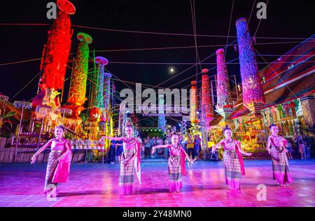 Gli artisti hanno visto vestirsi con costumi locali tradizionali durante il Salak Yom Festival del 2024 al Wat Phra That Hariphunchai Woramahawihan, a Lamphun. Il Salak Yom Festival è una cerimonia locale unica che si trova solo a Lamphun, in Thailandia, e in nessun altro posto al mondo. Radicato nel buddismo e nella cultura Lanna, l'evento è una tradizione annuale di produzione di meriti che si tiene prima della fine della Quaresima buddista. Consiste nell'offrire oggetti speciali ai monaci collocandoli in pali di bambù riccamente decorati, noti come "Salak Yom". Questo assomiglia alla pratica buddista dell'offerta di Kathina Robe. L'obiettivo principale del Salak Yom ce Foto Stock