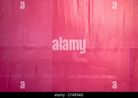 Poster di carta rosa incollato su una struttura della parete Foto Stock