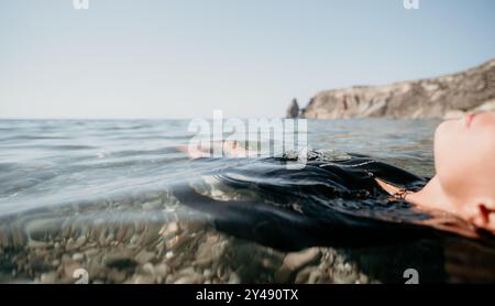 Donna, Mare, relax - Una donna galleggia a faccia in su nell'oceano, godendosi l'acqua calma e tranquilla. Foto Stock