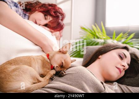 Riposo tranquillo condiviso da due donne e un cucciolo, le loro espressioni sono morbide e rilassate Foto Stock