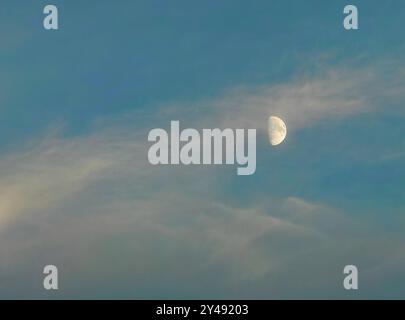 Fase Half Moon: Satellite della Terra contro un cielo blu nuvoloso Foto Stock