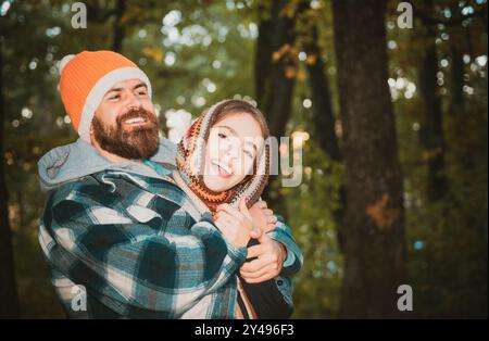 Atmosfera accogliente e ispirazione autunnale. Felice sorridente e avvolgente coppia in caldo cappello a maglia e sciarpa che camminano all'aperto nella foresta autunnale. Giallo Foto Stock