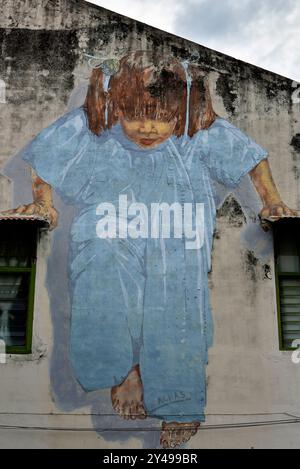 Murales giocosi e Street art di George Town, Penang, Malesia. Bambino in pigiama blu sostenuto dai finestrini Foto Stock