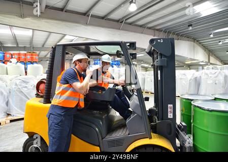 Gruppo di lavoratori nell'industria logistica lavorare in un magazzino con prodotti chimici - Sollevamento del carrello Foto Stock