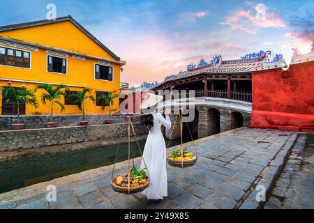 Donna asiatica che indossa la cultura tradizionale del vietnam e vende la frutta per strada, Hoi An in Vietnam. Foto Stock