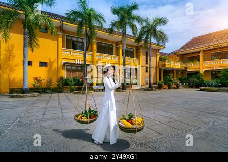 Donna asiatica che indossa la cultura tradizionale del vietnam e vende la frutta per strada, Hoi An in Vietnam. Foto Stock