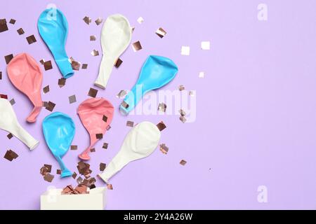 Coriandoli lucenti e palloncini sgonfiati che volano fuori da una piccola scatola su sfondo viola, piatto. Spazio per il testo Foto Stock